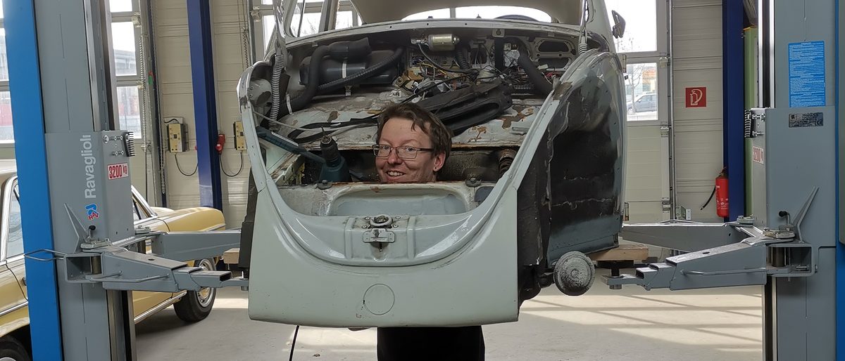 Rückenwind dank Meistergründungsprämie Stefan Werne schaut durch Oldtimer-Karosserie in die Kamera.