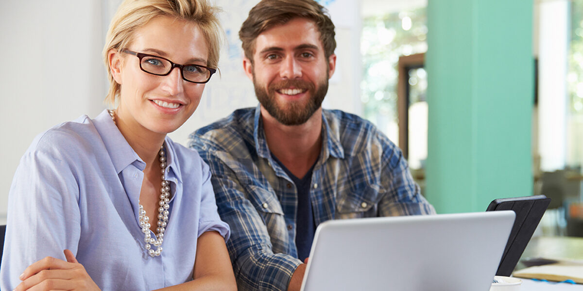 Symbolbild für das Beratungsangebot der Bildungsakademie: Frau und Mann vor Laptop lächeln in die Kamera.