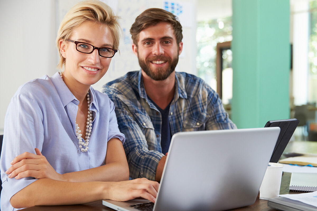 Symbolbild für das Beratungsangebot der Bildungsakademie: Frau und Mann vor Laptop lächeln in die Kamera.