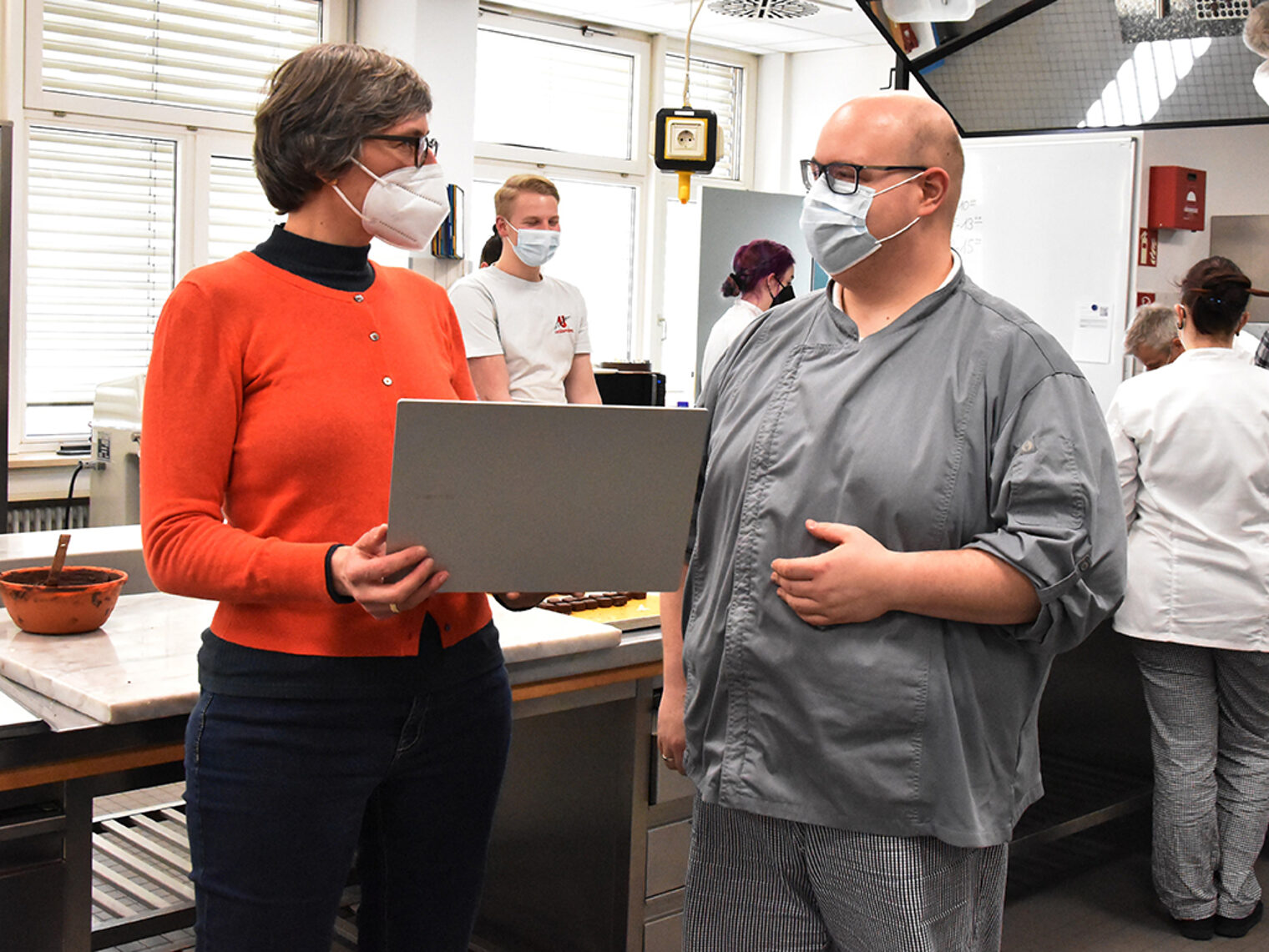 Maria Kreiner und Simon Rapp stehen mit Laptop in der Hand in der Bildungsakademie Rottweil.