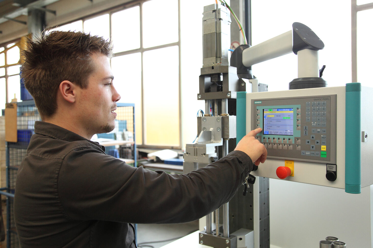 Junger Feinwerkmechaniker bedient Maschine.