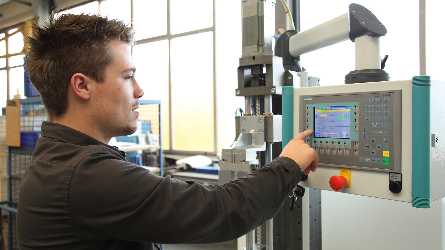 Junger Feinwerkmechaniker bedient Maschine.