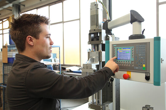 Junger Feinwerkmechaniker bedient Maschine.