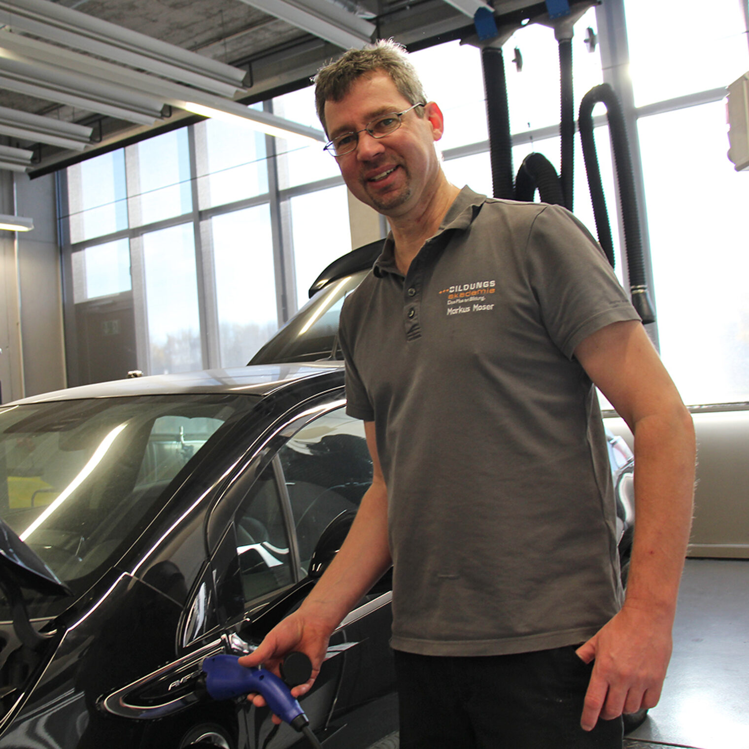 Markus Moser, Ausbilder für Kfz an der Bildungsakademie Singen, mit einem Auto.