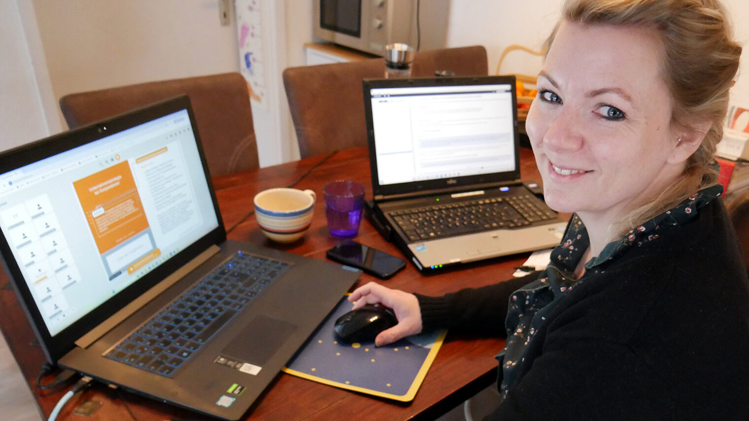 Sabrina Herres am Schreibtisch zuhause mit zwei geöffneten Laptops.