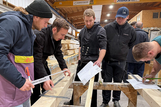 Studenten und Handwerksmeisterschüler arbeiten gemeinsam an der Konstruktion eines Fachwerkknotens.