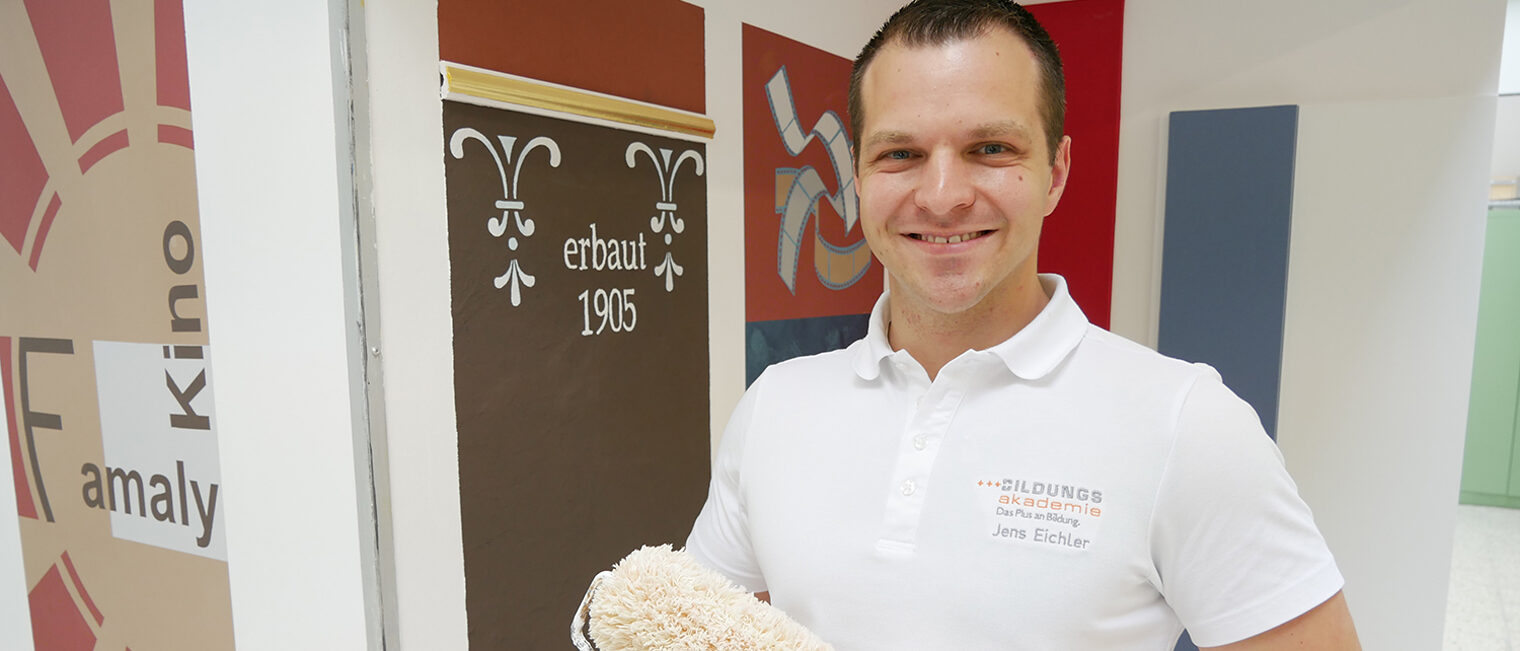 Portrait von Jens Eichler mit Malerrolle in der Hand.