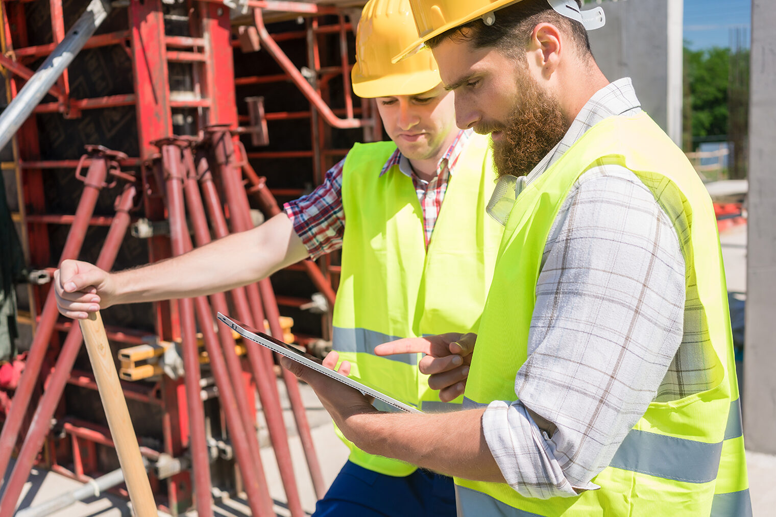 Zwei junge Bauarbeiter mit einem Tablet auf der Baustelle