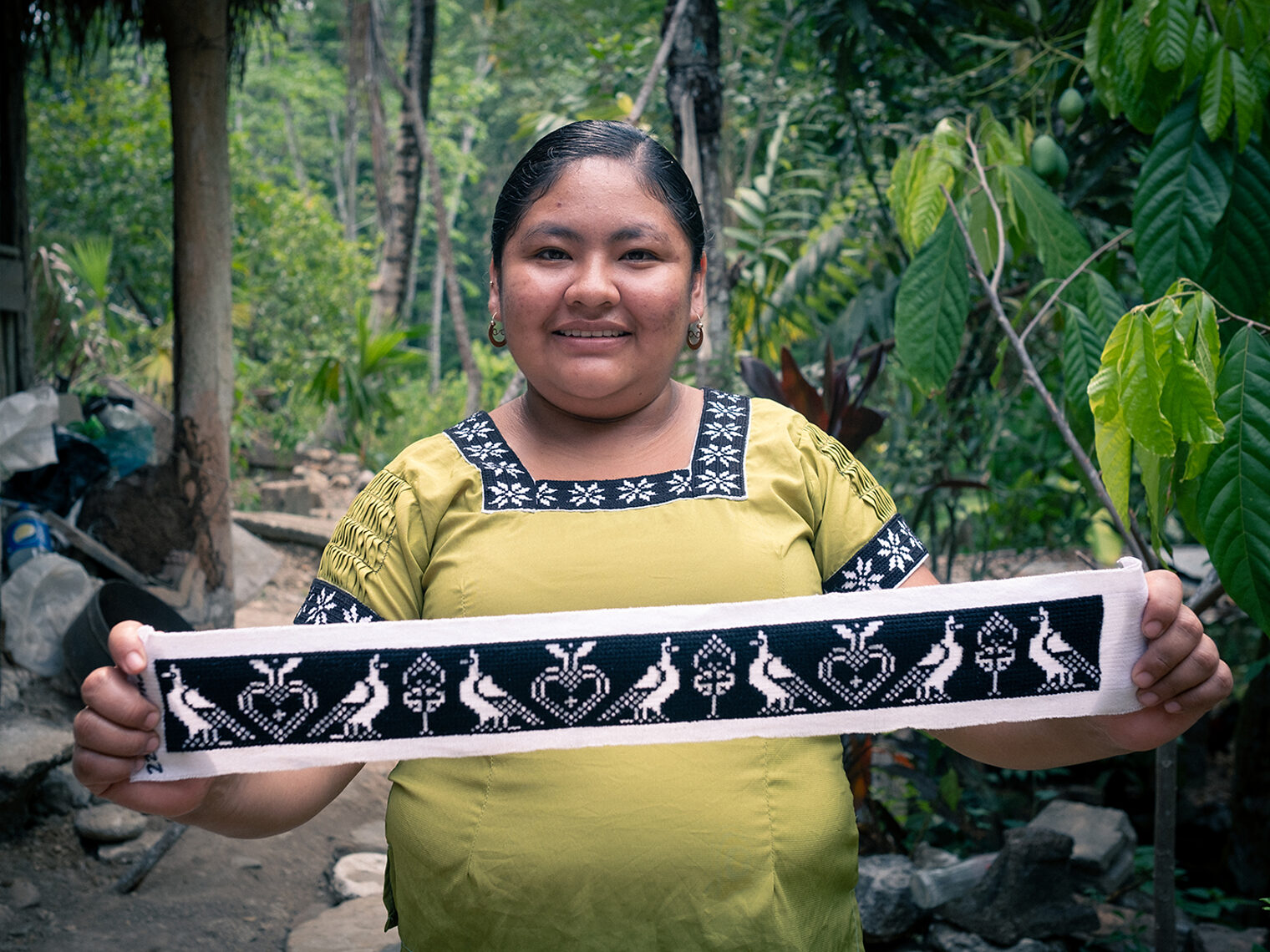  Maya-Frau in Belize im Regenwald hält besticktes Band in die Kamera