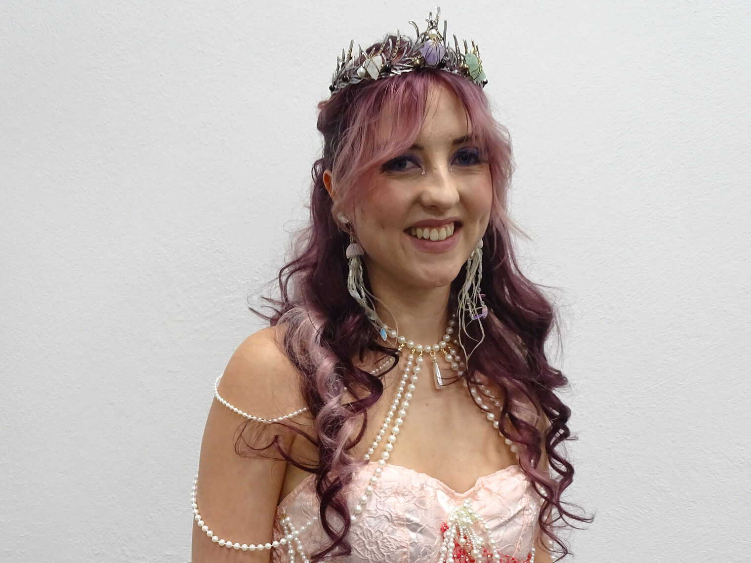 Als Meerjungfrau gestylte Frau mit langen Locken und Krönchen.