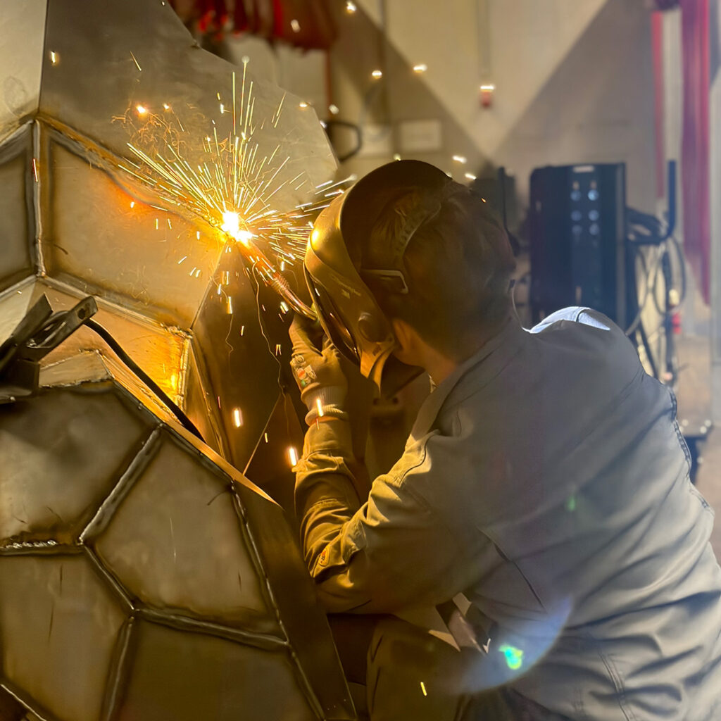 Ein Metallbauer-Ausbildender schweißt einen lebensgroßen Gorilla im MAG-Verfahren.