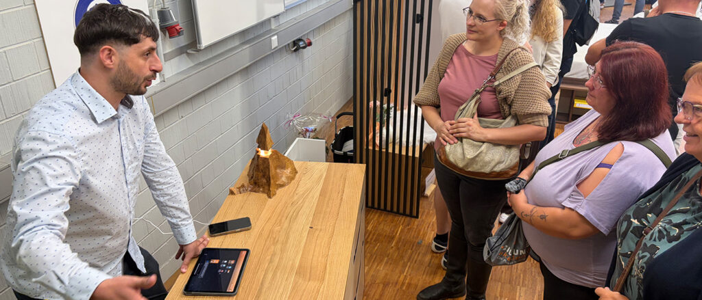 Schreiner erklärt sein Meisterstück drei interessierten Frauen bei der Meisterstückausstellung in der Bildungsakademie Waldshut.